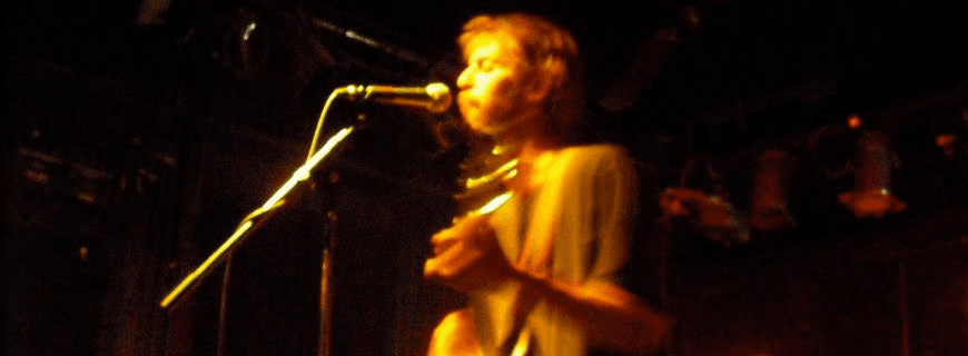 Kevin Long playing guitar and singing into a microphone